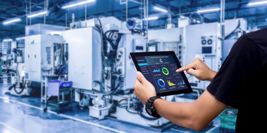 Hands holding tablet on blurred automation machine as background