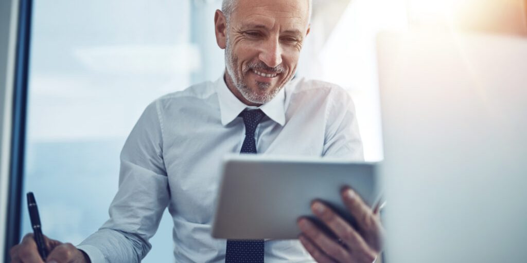 Shot of a businessman sitting at his desk using a digital tablet
